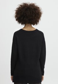 Czarny sweter z dzianiny o lekko oversize'owym kroju, prążkowanej teksturze u dołu i okrągłym dekolcie. Miękka tkanina, minimalistyczny design.