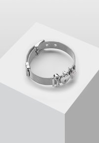 Bracciale in rete argentata con ciondolo a forma di cuore, accentuato da una piccola perla e chiusura liscia con finitura metallica.