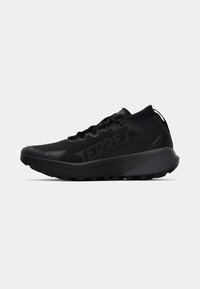 Schwarze Sportschuhe mit einem strukturierten, atmungsaktiven Obermaterial und "TERREX"-Logo. Das Design verfügt über eine gepolsterte Sohle und eine robuste Außensohle für besseren Halt.