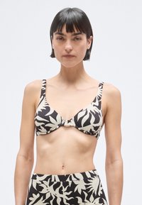 Sort og cremefarvet bikinitop med mønster og tekstureret finish, der har brede stropper, en indsnøret midte og trekantsform.