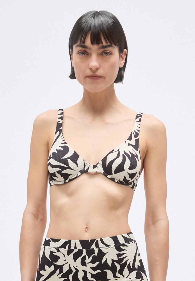 Sort og cremefarvet bikinitop med mønster og tekstureret finish, der har brede stropper, en indsnøret midte og trekantsform.