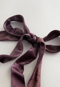 Ruban en satin violet noué en un nœud, avec une texture lisse et un détail en tulle contrastant d'un côté. Plat, avec des extrémités lâches.