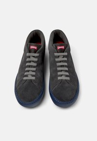 Gray suede shoes with gray laces and a blue sole, featuring a red "Camper" logo on the tongue, displayed from above on a white background.
