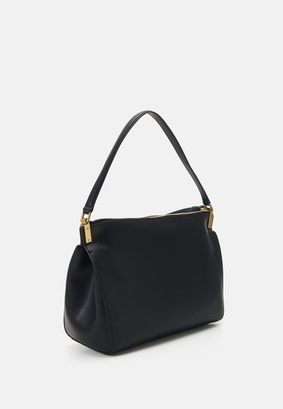 Melna ādas rokassoma ar gludu tekstūru, vienu izliekta rokturi un zeltainiem aksesuāriem. Aprīkota ar rāvējslēdzēja augšdaļu.