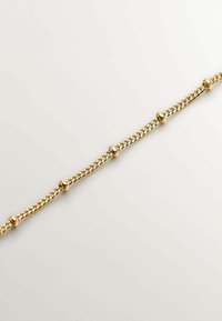 Pulsera de cadena de oro con pequeños acentos redondos, diseño intrincadamente enlazado y un acabado suave, que muestra una superficie pulida y reflectante.