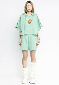 Sudadera verde menta de gran tamaño con un estampado de oso, pantalones cortos a juego y calcetines blancos hasta la rodilla. Tejido suave con un ajuste relajado.