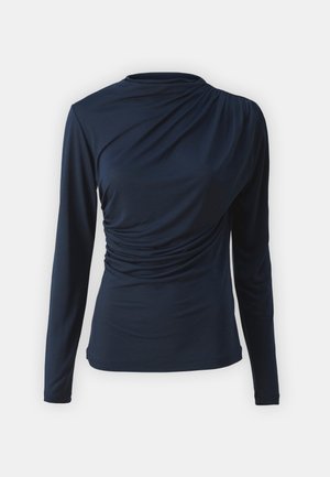 Haut à manches longues bleu marine avec un col montant, présentant un tissu froncé d'un côté et une texture lisse, conçu avec une silhouette ajustée.
