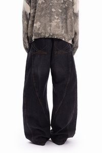 Φαρδιά, σκουρόχρωμα τζιν με υφή και καμπυλωτές ραφές. Συνδυασμένα με γκρι και μπεζ πουλόβερ με σχέδιο.