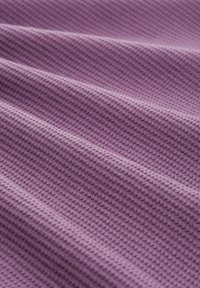 Tessuto viola strutturato con un motivo a nido d'ape, caratterizzato da ondulazioni e pieghe che ne esaltano l'aspetto tridimensionale.