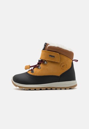 Botte d'hiver pour enfant avec semelle noire, dessus en cuir marron, fermeture lacets et velcro, et doublure en polaire blanche à l'intérieur.