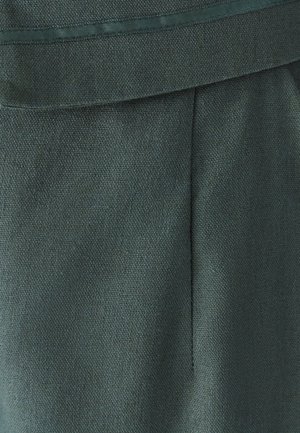 Tmavě zelená látka s texturovaným povrchem, která má hladký pas a jemný skládací detail pro elegantní vzhled.