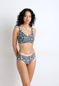 Bikini set met luipaardprint, bestaande uit een bralette met v-hals en verstelbare bandjes, en een mid-rise broekje, gemaakt van rekbare stof met een zachte textuur.
