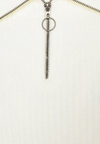 Witte ritssluiting kleding met een opvallende zilveren rits en een ronde trekker, ribbelstructuur en een aansluitend ontwerp.