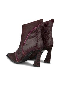 Botas de tobillo burdeos que combinan texturas de cuero y estampado animal, acentuadas con tachuelas moradas y gruesos tacones con estampado de leopardo.