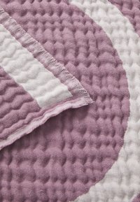 Coperta intrecciata in lavanda e bianco, caratterizzata da un motivo testurizzato con un design ondulato e bordi frangiati. Materiale morbido e leggero.