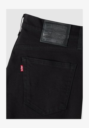 Czarne dżinsy Levi's, pokazujące prawą tylną kieszeń z czerwoną metką Levi's i czarną skórzaną naszywką marki z rozmiarem W32 L.