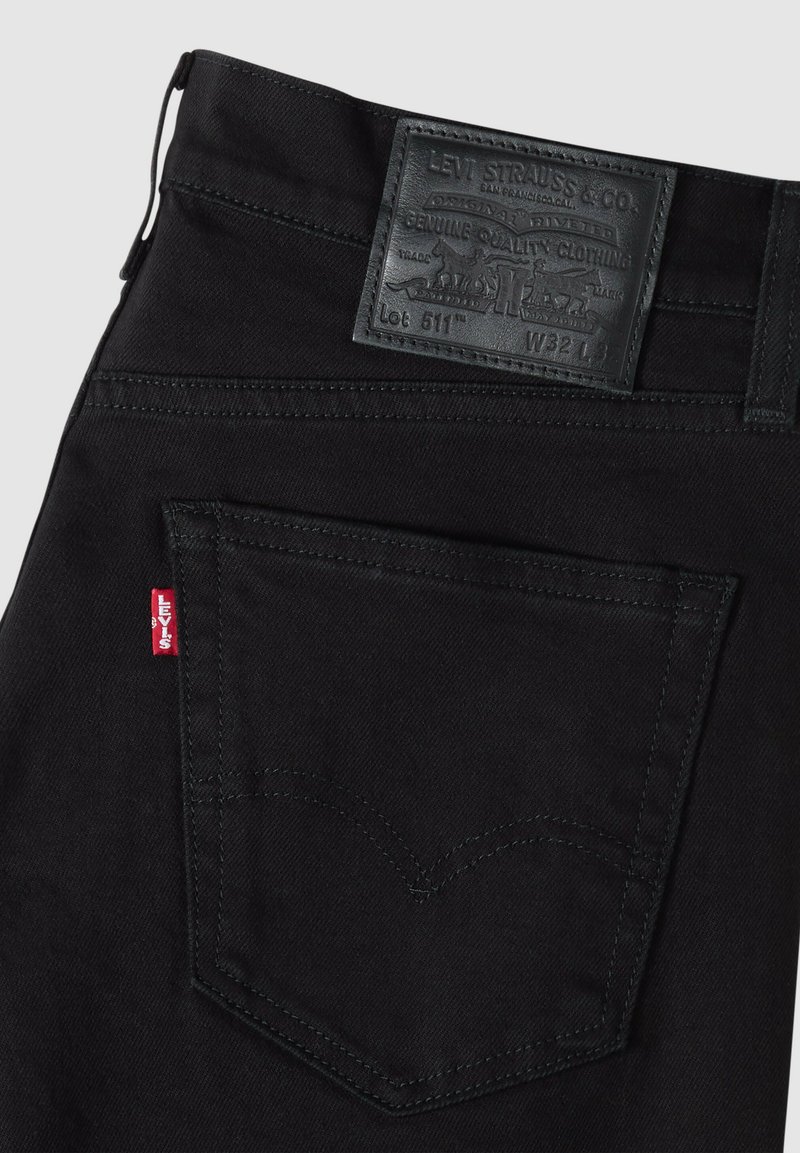 Schwarze Levi's-Jeans, Rückseite rechte Tasche mit rotem Levi's-Tag und schwarzem Leder-Brandpatch mit Größe W32 L.