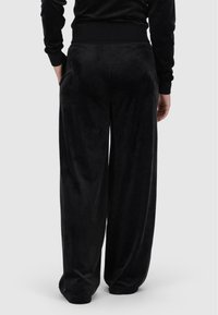 Melna velūra platās kājas bikses ar elastīgu jostu un sānu kabatām, ar mīkstu tekstūru un brīvu piegriezumu.