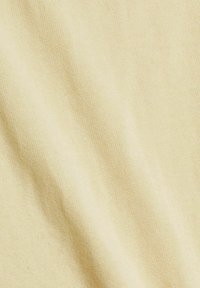 Texture de tissu douce et jaune clair avec un motif de tricot fin et des plis délicats créant des ombres subtiles.