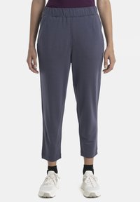 Pantalons de jogging légers bleu marine, dotés d'une taille élastique, de jambes fuselées et de deux poches latérales, portés avec des chaussures de sport blanches.