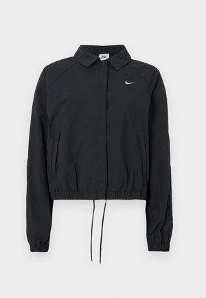 Giacca corta Nike nera con collo a camicia, polsini elastici e orlo con coulisse; presenta il logo sul petto; texture del tessuto liscia.