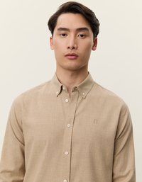 Bežinė marškinė su užsegimu, pagaminti iš tekstūruotos medžiagos, su apykakle, baltais mygtukais ir išsiuvinėtu logotipu kairiajame krūtinės šone.