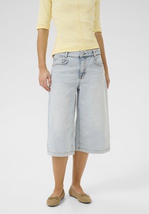 Lyseblå denim culotter med høj talje, der har knap- og lynlåslukning, forlommer og vide ben, kombineret med en gul top.