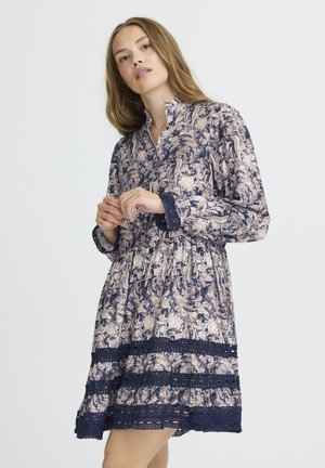 Robe à manches longues bleu marine avec un motif floral en rose et crème. Présente un col et des accents en dentelle à l'ourlet et aux manches.