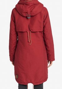Lange rode parka met capuchon, met een verkorte achterkant, verstelbare trekkoorden en een label aan de zoom. Glad textuur.