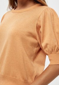 Maglione a pullover di colore pesca con maniche a sbuffo corte, colletto e orlo a coste e una texture morbida. Design semplice, senza motivi visibili.