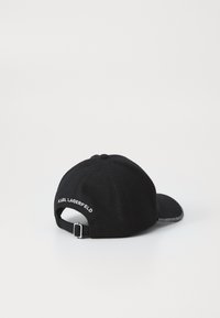 Casquette de baseball en laine noire avec une visière incurvée, arborant le texte brodé en blanc "KARL LAGERFELD." Sangle ajustable à l'arrière.