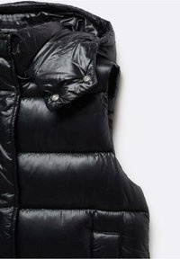 Doudoune sans manches noire brillante matelassée avec col montant et boutons-pression sur la capuche amovible, présentée sur un fond blanc.