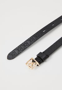 Cintura in ecopelle nera con motivo impresso e fibbia quadrata dorata con dettaglio del logo. Progettata con più fori di regolazione.