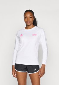 Hvid langærmet skjorte med pink "BMW Berlin Marathon" logo og sorte shorts med hvide detaljer og Adidas-logo på siden.