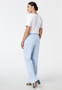 Lichtblauwe high-waisted broek met een gladde textuur, voorzien van zijzakken en een ontspannen pasvorm. Gepaard met een witte crop top.