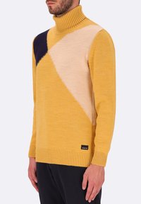 Maglione giallo a collo alto con un design geometrico a blocchi di colore, in blu marino, beige e dalla consistenza morbida. Polsini e orlo a costine.