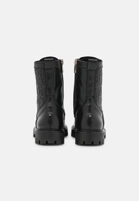 Stivali alla caviglia in pelle nera con pannelli laterali testurizzati, chiusura con zip e suola robusta. Presentano un piccolo dettaglio del logo vicino al tallone.