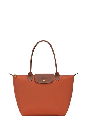 Orange Nylon-Tasche mit braunen Lederelementen, zwei Griffen, einem oberen Reißverschluss und einer Druckknopfklappe mit einem goldenen Knopf. 