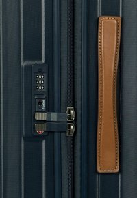 Valigia blu navy con esterno texturizzato, doppie cerniere, lucchetto a combinazione e manico in pelle marrone a contrasto.