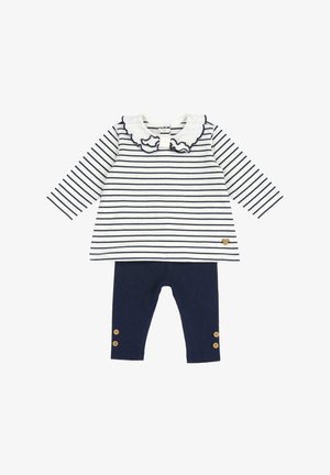 Maglietta a maniche lunghe a righe bianca e blu navy, con colletto arricciato; abbinata a leggings blu navy con dettagli di bottoni in legno alla caviglia.