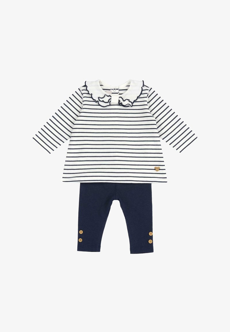 Maglietta a maniche lunghe a righe bianca e blu navy, con colletto arricciato; abbinata a leggings blu navy con dettagli di bottoni in legno alla caviglia.