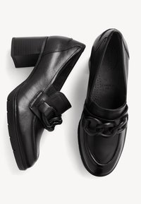 Black leather heeled shoes with a chunky chain detail across the front. Features a wide fit and textured, ridged heel.