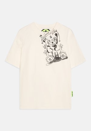 T-shirt en coton couleur crème avec un croquis noir d'un ours et du texte. Manches courtes et une étiquette de marque vert néon sur le côté.