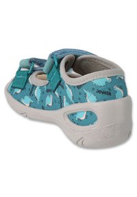 Lekki dziecięcy but w tealowym kolorze z nadrukiem dinozaurów, szarym gumowym spodem, dwoma regulowanymi paskami na rzepy oraz wyściełanym wsparciem kostki.