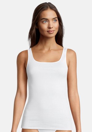Young woman with long brown hair wearing a sleeveless white tank top, looking slightly to the right against a plain background.