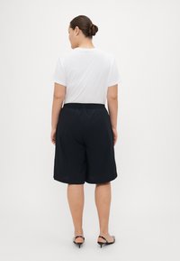 Black shorts with elastic waistband paired with a white t-shirt. The shorts are knee-length and made of lightweight fabric.