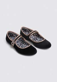Bailarinas de terciopelo negro con una correa y hebilla en tono marrón, que presentan un forro de estampado de leopardo, punta redondeada y suelas planas.