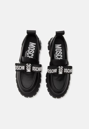 Coppia di mocassini neri chunky con suole spesse e cinturini neri con scritta bianca "Moschino" sulla parte anteriore.