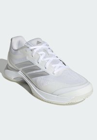 Biały but sportowy z fakturowaną cholewką, srebrnymi, odblaskowymi akcentami, amortyzowaną podeszwą oraz sznurowanym wiązaniem dla pewnego dopasowania.