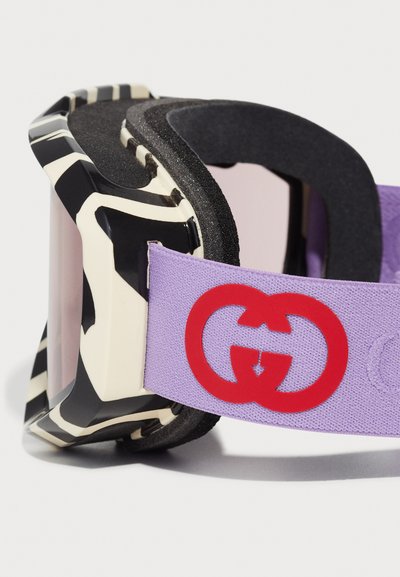Occhiali da sci Gucci con un design astratto nero e avorio, fascia viola, logo rosso e interno in schiuma imbottita per comfort e vestibilità.
